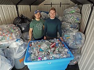 Two Ƶ students standing behind a large container filled with cans to be recycled